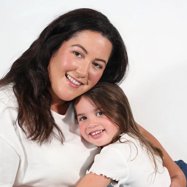 Genesis Joly smiling and holding her daughter